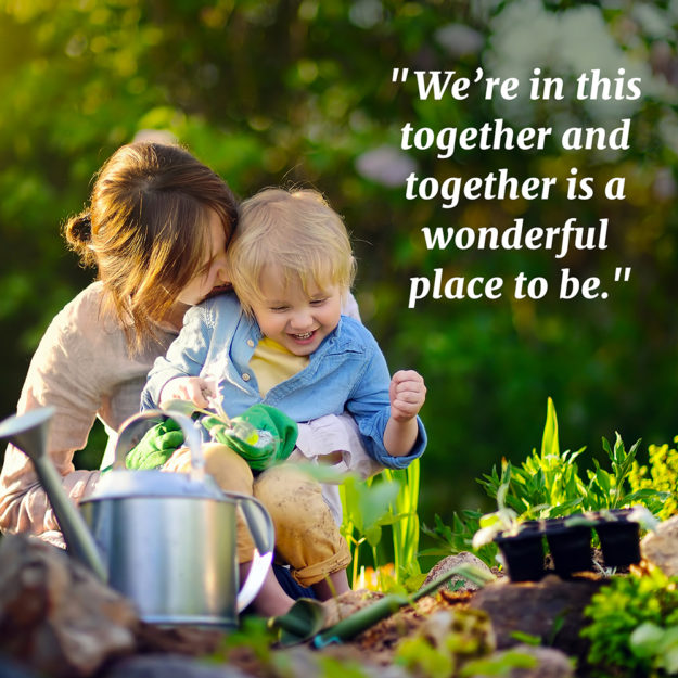 Beautiful young woman and her cute son planting seedlings in bed in the domestic garden at summer day Family Gardening